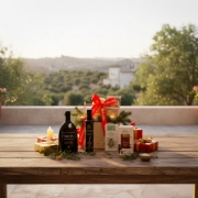 Artisanal Greek food gift basket on a wooden table overlooking a serene Cretan landscape at sunset.
