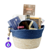 Full view of The Aegean Blue Collection gourmet gift basket by Elenianna, featuring a blue wicker hamper with an evil eye charm, filled with Kyklopas olive oil, Cretan pasta, organic figs, and sea salt on a white background.