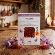 Premium Krokos Kozanis red saffron filaments and purple crocus flowers on a rustic wooden kitchen table, showcasing artisanal Greek quality.