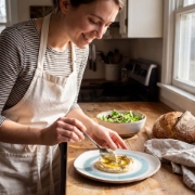 A woman enjoying a fresh salad served on an organic-shaped Aegean Eye ceramic plate at a wooden table.